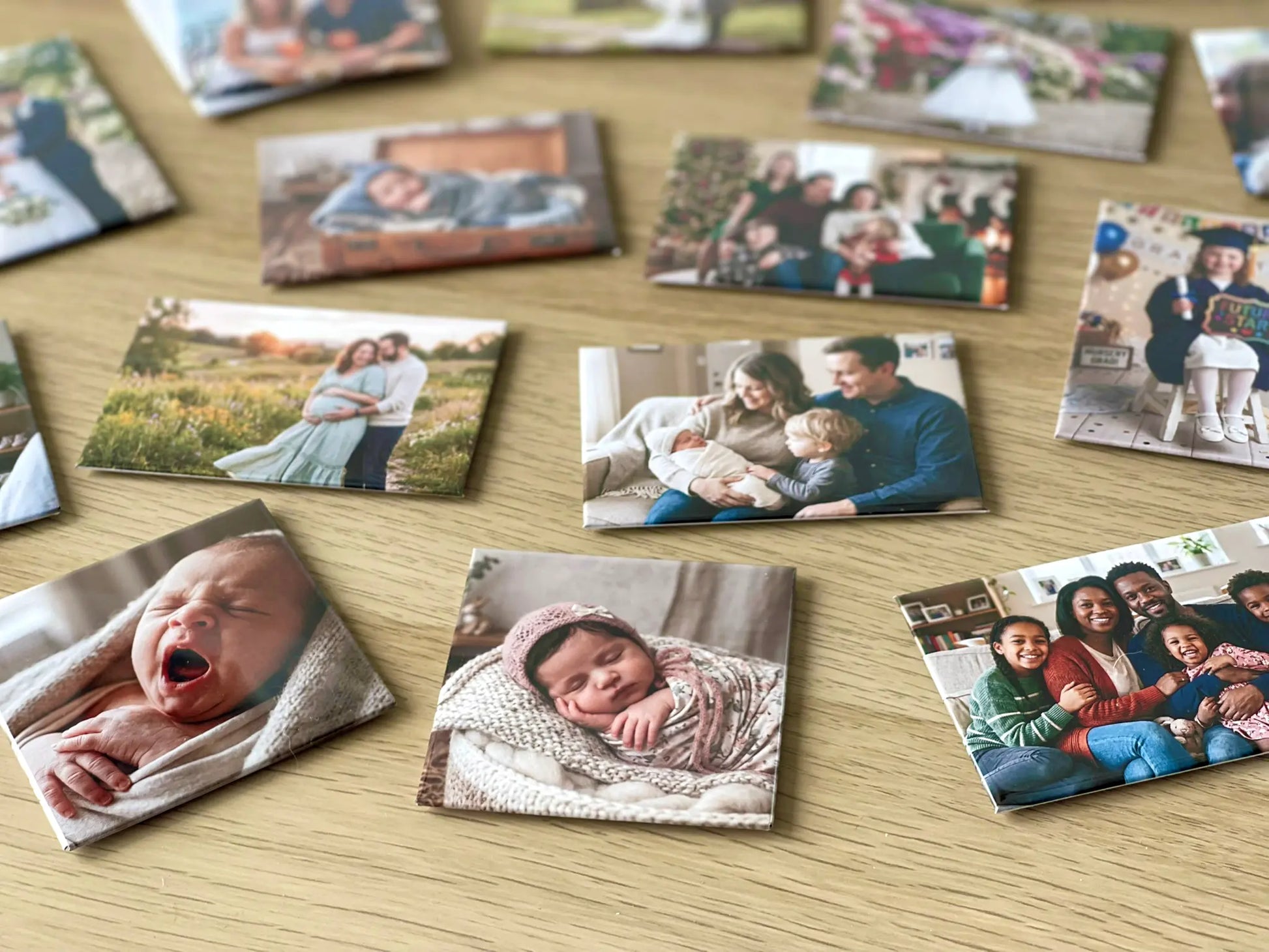 A close-up view of square personalized fridge magnets resting on a wooden table, focusing sharply on a beautifully detailed, high-gloss photo magnet of a sleeping newborn baby in the foreground.