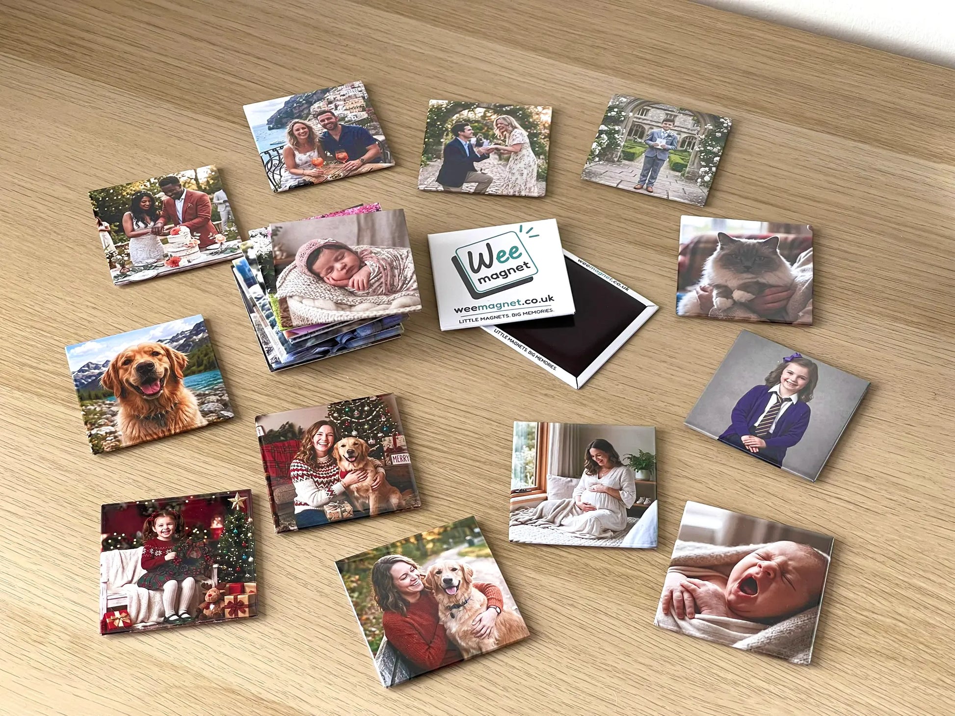 A diverse collection of square personalized photo fridge magnets scattered on a wooden surface around a Wee Magnet brand magnet, showcasing vibrant wedding, pet, family, and baby portraits.